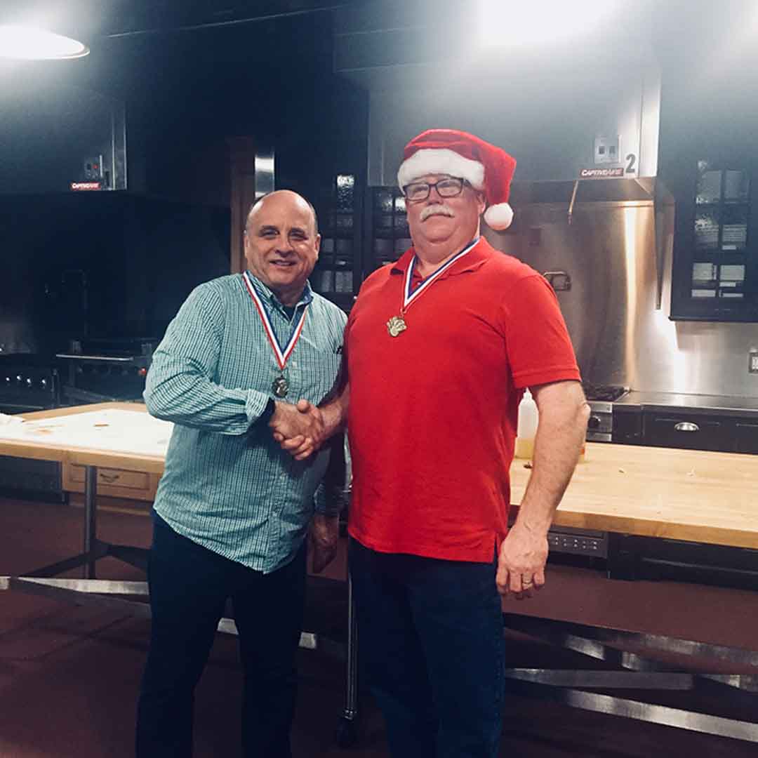 Men shaking hands with medals after team building event at Mirepoix above Holiday Market Royal Oak